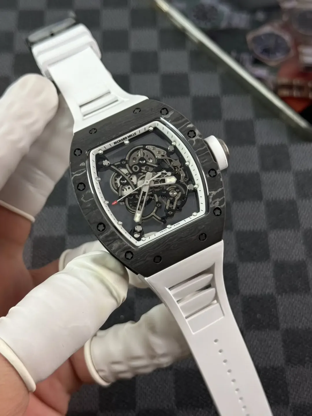RM 055 white carbon composite case with white rubber strap held in a gloved hand